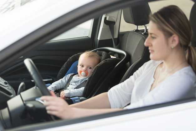 Femme au volant d'une voiture avec bébé assis sur le siège avant