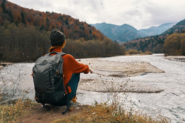 Femme à l'automne dans les montagnes avec un sac à dos sur ses épaules modèle de rivière tourisme voyage