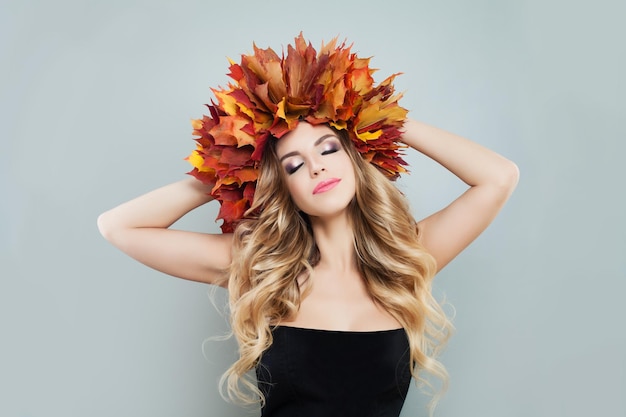 Femme d'automne portant une couronne de feuilles d'automne colorées sur fond gris