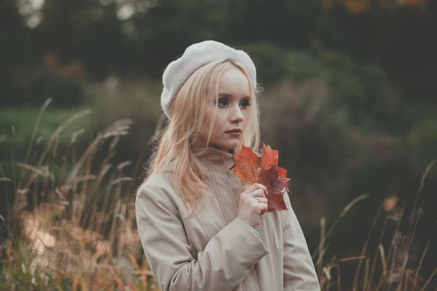 Femme d'automne réfléchie avec des feuilles d'autumn sur le fond de la nature automnale