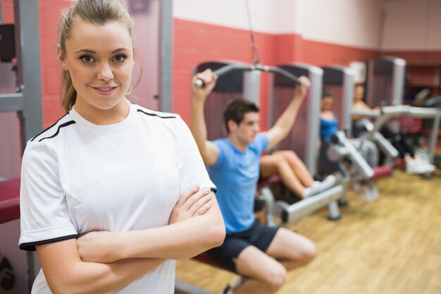 Femme aux bras croisés debout dans un studio de remise en forme