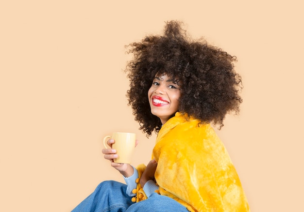 Femme aux cheveux afro buvant une couverture de café