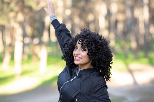 Femme aux cheveux afro, dans la forêt s'amusant heureux