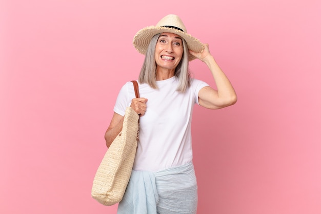 Femme aux cheveux blancs d'âge moyen se sentant stressée, anxieuse ou effrayée, les mains sur la tête. concept d'été