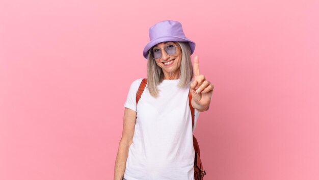 Femme aux cheveux blancs d'âge moyen souriant fièrement et en toute confiance faisant le numéro un. notion d'été