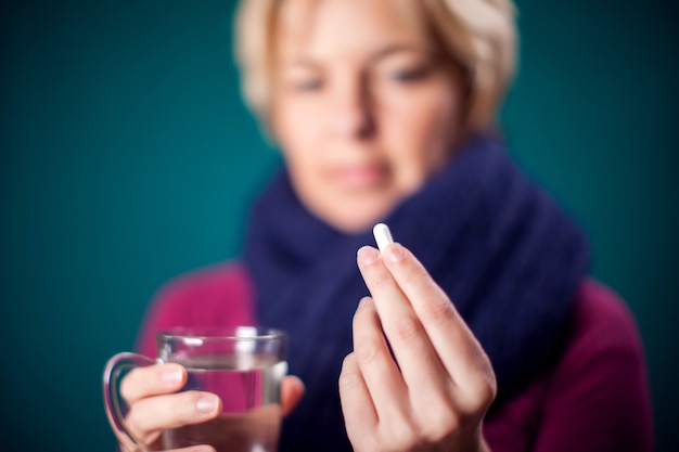 Une femme aux cheveux blonds courts a attrapé la grippe et prend une pilule. Concept de personnes, de soins de santé et de médecine