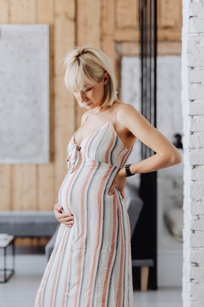 Femme aux cheveux blonds enceinte dans un salon