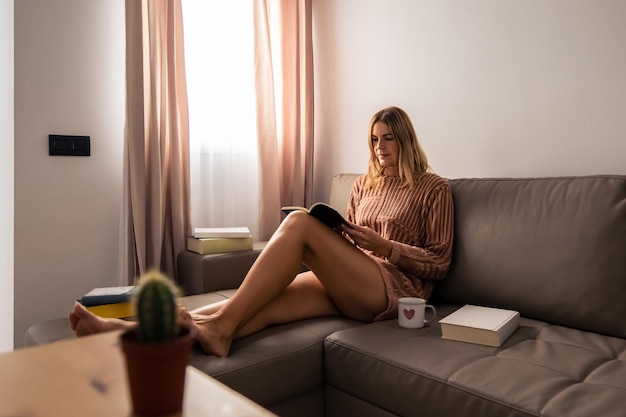 Femme aux cheveux blonds lisant calmement par la fenêtre