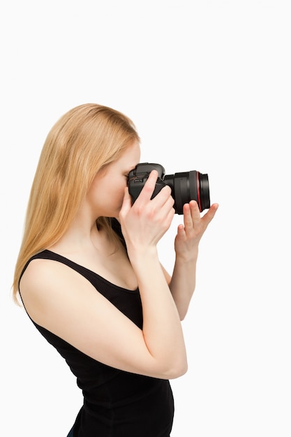 Femme aux cheveux blonds visant avec un appareil photo