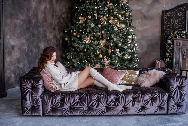 femme aux cheveux bouclés assis sur le canapé à la période de Noël