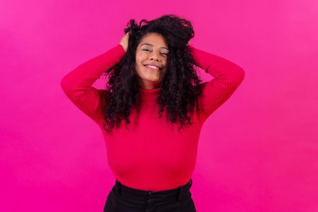 Femme aux cheveux bouclés sur un fond rose tourné en studio style de vie