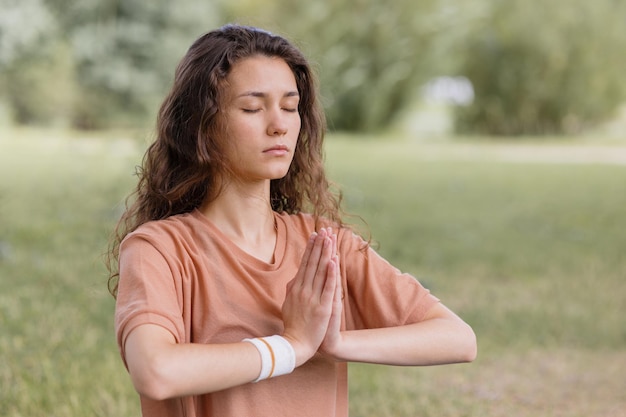 Femme aux cheveux bouclés médite dans le parc yoga et méditation pour la santé mentale et physique a