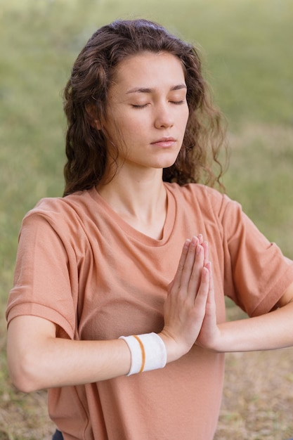 Femme aux cheveux bouclés médite dans un parc yoga et méditation pour la santé mentale et physique