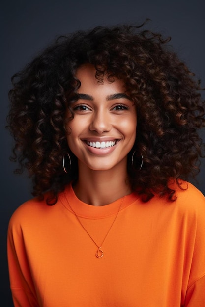 une femme aux cheveux bouclés portant une chemise orange avec des boucles d'oreilles