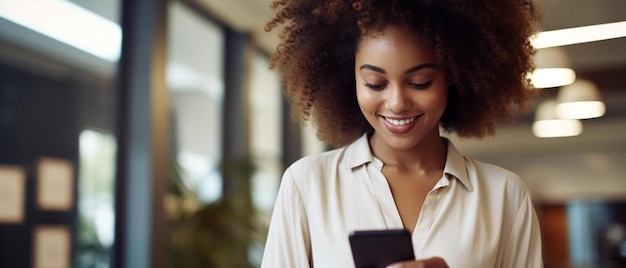 une femme aux cheveux bouclés regarde un téléphone et sourit