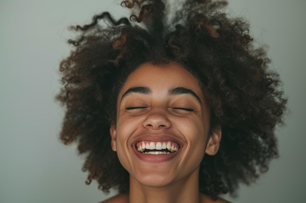 Une femme aux cheveux bouclés sourit et a la bouche ouverte.