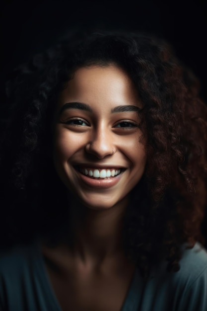 Une femme aux cheveux bouclés sourit devant un fond noir.