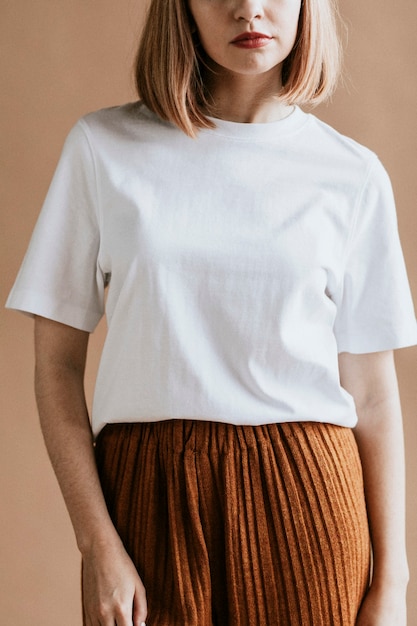 Femme aux cheveux bruns courts dans un tee-shirt blanc et une jupe marron