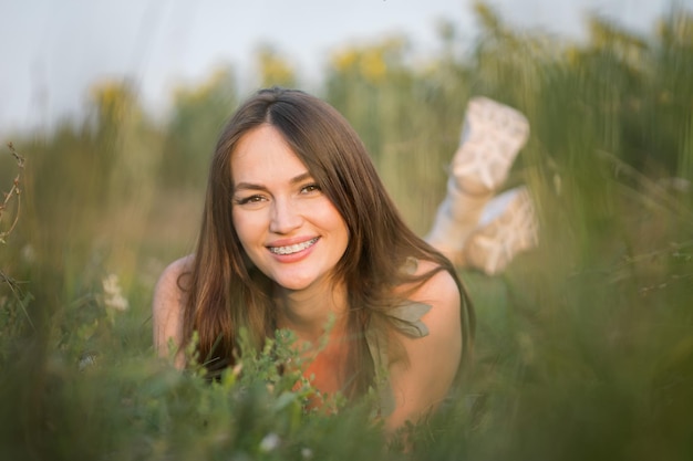 Une femme aux cheveux bruns se trouve sur l'herbe en admirant le paysage des prairies