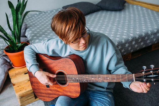 femme aux cheveux courts aime jouer de la guitare à la maison leçons de musique pour adultes