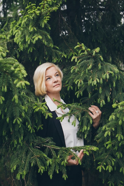 femme aux cheveux courts blanc parmi les arbres.