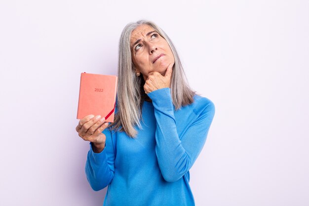 Femme aux cheveux gris d'âge moyen pensant, se sentant dubitative et confuse. concept d'agenda 2022