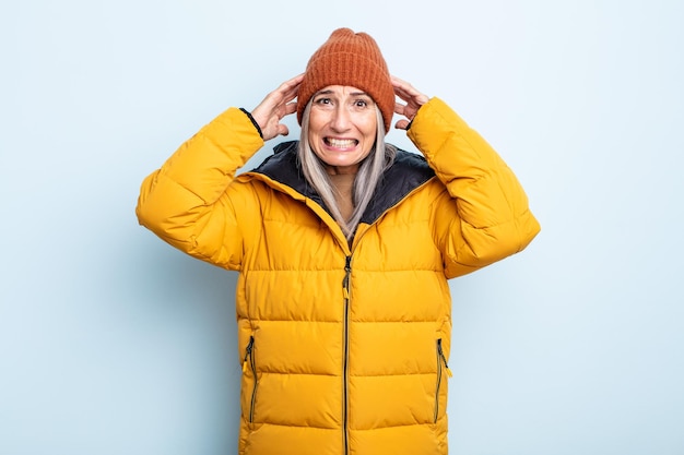 Femme aux cheveux gris d'âge moyen se sentant stressée, anxieuse ou effrayée, les mains sur la tête. concept de temps froid