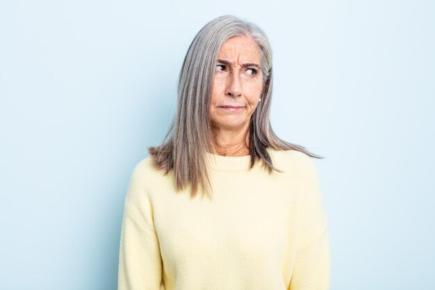 Femme aux cheveux gris d'âge moyen se sentant triste, contrariée ou en colère et regardant de côté avec une attitude négative, fronçant les sourcils en désaccord