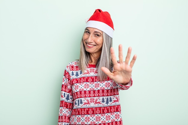 Femme aux cheveux gris d'âge moyen souriante et semblant amicale, montrant le numéro cinq. notion de noël