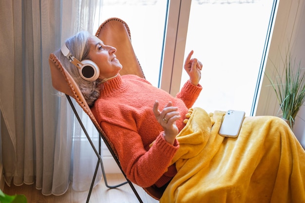 Femme aux cheveux gris profitant de son temps libre en écoutant de la musique via des écouteurs sans fil Concept technologie liberté relaxation