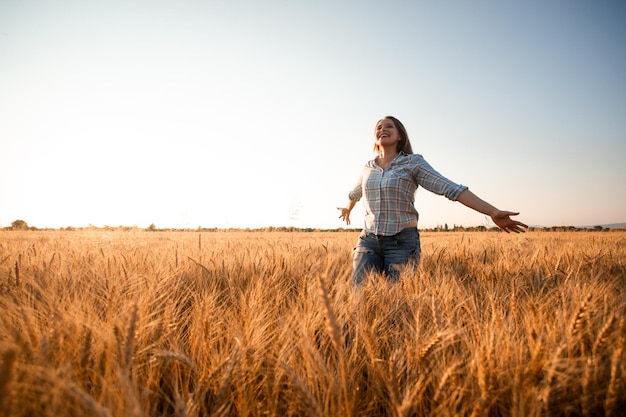 Femme aux cheveux longs dans le champ au coucher du soleil