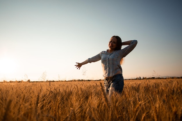 Femme aux cheveux longs dans le champ au coucher du soleil