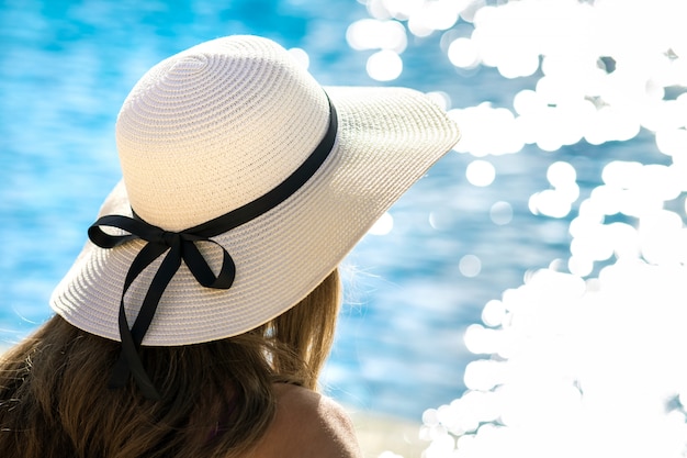 Femme aux cheveux longs portant un chapeau de plage près de la piscine