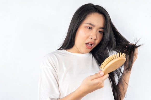 Une femme aux cheveux longs se brosse les cheveux avec une brosse en bois.