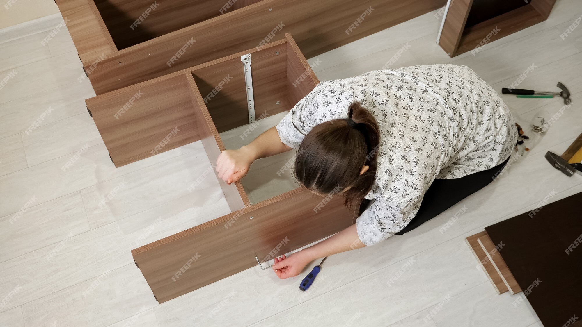 Une Femme Aux Cheveux Noirs Est Assise Sur Le Sol Et Assemble Un Nouvel Outil  Rotatif D'armoire Préfabriquée Pour Connecter Les Parties De L'étagère Vue  Supérieure