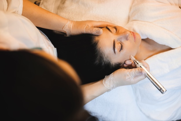 Photo femme aux cheveux noirs a une procédure spa pour ses soins de la peau du visage