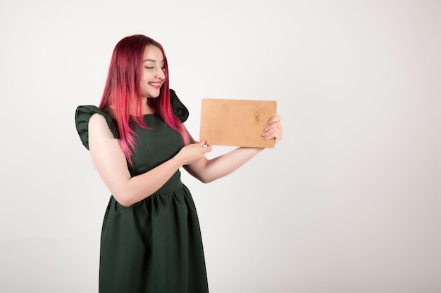 Femme aux cheveux roses sur blanc tenant un livre