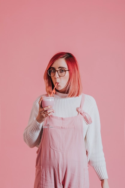 Femme aux cheveux roses buvant un smoothie