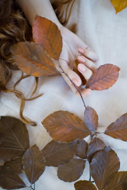 Femme aux cheveux roux bouclés toucher la branche avec des feuilles d'automne