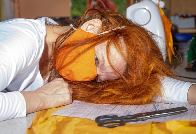 Photo une femme aux cheveux roux porte un respirateur médical. elle est épuisée.