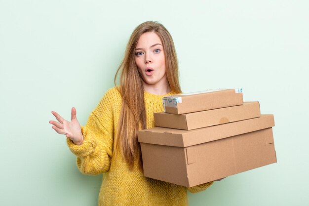 femme aux cheveux roux se sentant extrêmement choquée et surprise. concept de boîtes de colis