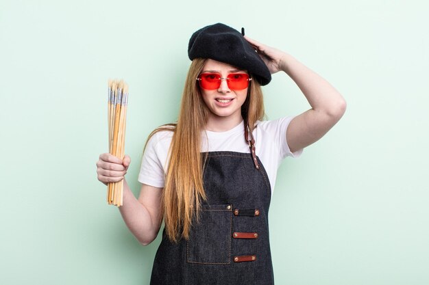 Femme aux cheveux roux se sentant stressée, anxieuse ou effrayée, avec les mains sur la tête. notion d'artiste