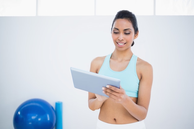 Femme aux cheveux sombre souriante avec sa tablette