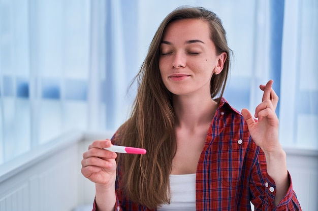 Femme aux doigts croisés attend un résultat de test de grossesse