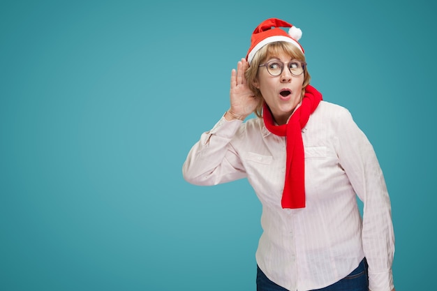 Femme aux écoutes. Une femme d'âge moyen dans la nouvelle année et des vêtements de Noël sur fond bleu