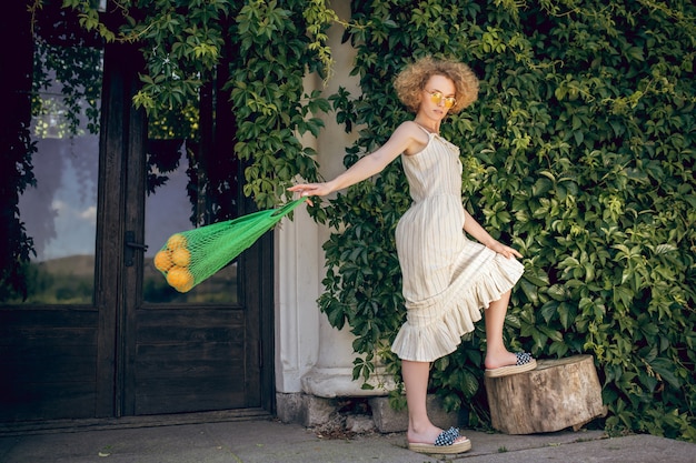 Femme aux fruits. Jeune femme tenant un sac en filet avec des fruits et à la réflexion