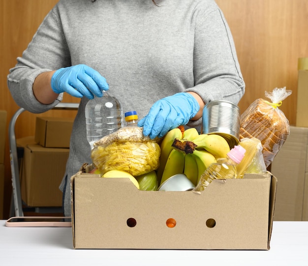 La femme aux gants continue de collecter de la nourriture, des fruits et des choses et une boîte en carton pour les aider.
