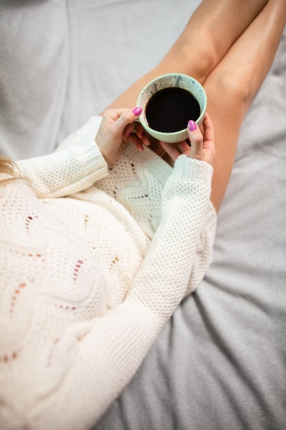 Une femme aux jambes en forme tient une tasse de café.