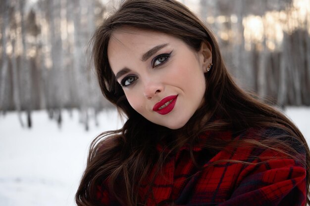 Femme aux lèvres rouges dans la forêt d'hiver