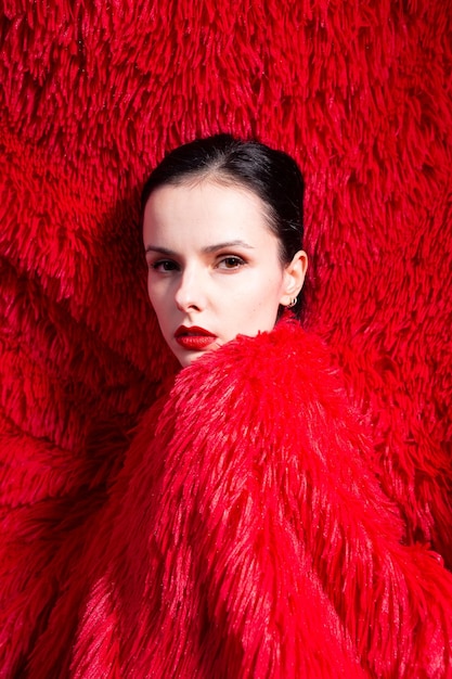 femme aux lèvres rouges dans des vêtements moelleux rouges fond moelleux rouge